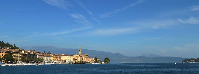 Trip Steiermark beliebte Urlaubsziele am Gardasee -  Mit einer Fläche von 370 km² ist der Gardasee der größte See Italiens. Es liegt am Fuße der Alpen und erstreckt sich über drei Staaten: Lombardei, Venetien und Trentino. Die maximale Tiefe des Sees beträgt 346 m, er hat eine längliche Form und sein nördliches Ende ist sehr schmal. Dort ist der See von den Bergen der Gruppo di Baldo umgeben. Du trittst aus deinem gemütlichen Hotelzimmer und es begrüßt dich die warme italienische Sonne. Du blickst auf den atemberaubenden Gardasee, der in zahlreichen Blautönen schimmert - von tiefem Dunkelblau bis zu funkelndem Türkis. Majestätische Berge umgeben dich, während die Brise sanft deine Haut streichelt und der Duft von blühenden Zitronenbäumen deine Nase kitzelt. Du schlenderst die malerischen, engen Gassen entlang, vorbei an farbenfrohen, blumengeschmückten Häusern. Vereinzelt unterbricht das fröhliche Lachen der Einheimischen die friedvolle Stille. Du fühlst dich wie in einem Traum, der nicht enden will. Jeder Schritt führt dich zu neuen Entdeckungen und Abenteuern. Du probierst die köstliche italienische Küche mit ihren frischen Zutaten und verführerischen Aromen. Die Sonne geht langsam unter und taucht den Himmel in ein leuchtendes Orange-rot - ein spektakulärer Anblick.